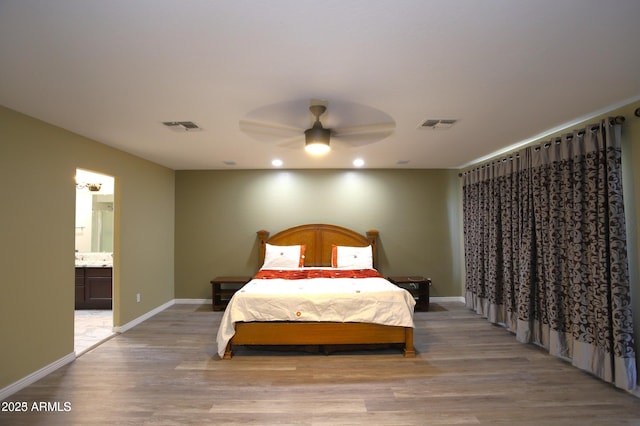 bedroom featuring light wood-style floors, baseboards, visible vents, and connected bathroom