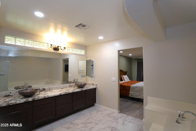 ensuite bathroom with marble finish floor, a sink, visible vents, and recessed lighting
