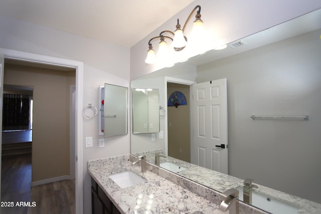 bathroom featuring wood finished floors, vanity, baseboards, and visible vents