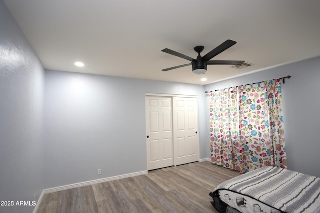 bedroom with a closet, baseboards, recessed lighting, visible vents, and wood finished floors
