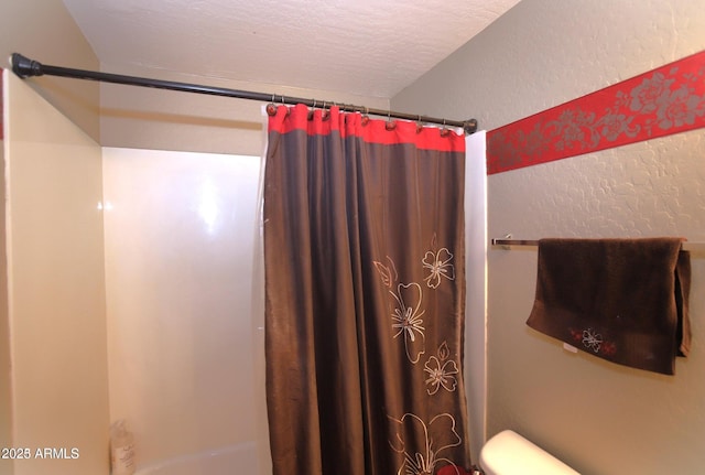 bathroom featuring toilet, curtained shower, a textured wall, and a textured ceiling