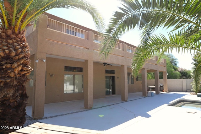 exterior space featuring a patio area, ceiling fan, fence, a balcony, and stucco siding
