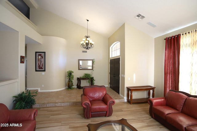 living area featuring visible vents, baseboards, a chandelier, light wood-style flooring, and high vaulted ceiling