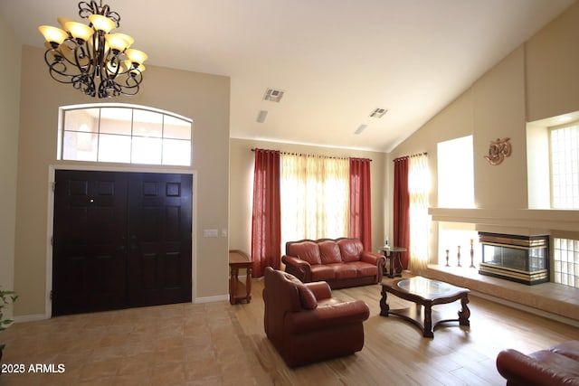 interior space with a multi sided fireplace, visible vents, an inviting chandelier, and lofted ceiling