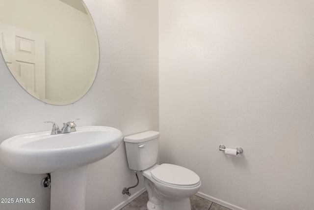half bath with toilet, tile patterned flooring, and baseboards