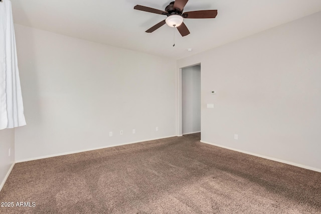 carpeted spare room with ceiling fan and baseboards