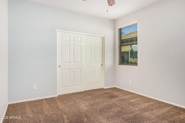 unfurnished bedroom featuring carpet floors, a closet, baseboards, and ceiling fan