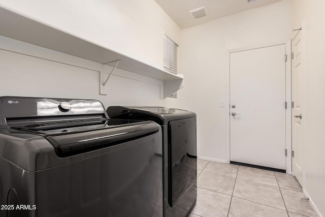 laundry room featuring washer and clothes dryer, light tile patterned floors, and baseboards