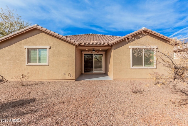 rear view of property featuring a ceiling fan, stucco siding, a tile roof, and a patio area