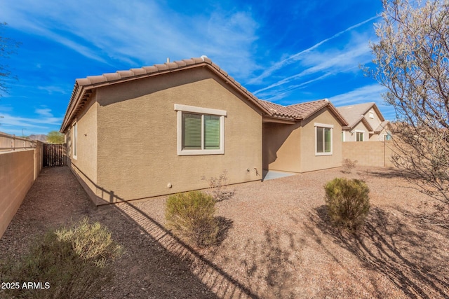 back of property with stucco siding, a fenced backyard, and a tile roof