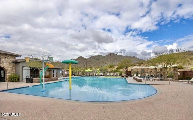 community pool with a mountain view and a patio area