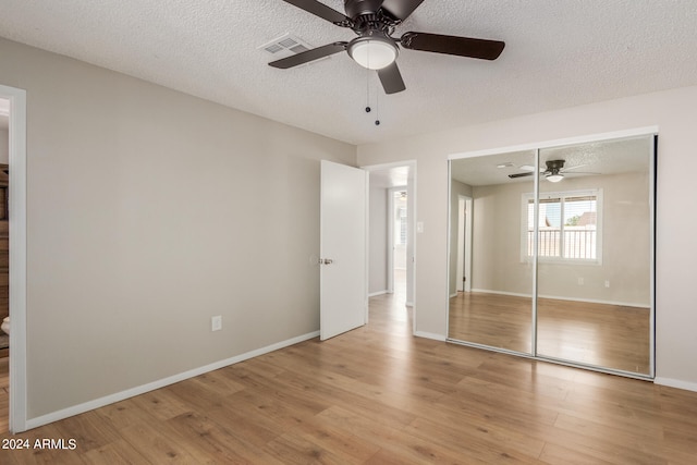 unfurnished bedroom with a closet, light hardwood / wood-style floors, ceiling fan, and a textured ceiling