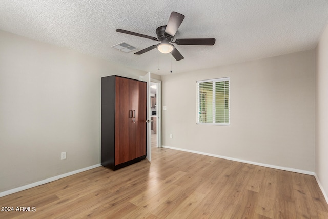 spare room featuring light hardwood / wood-style floors, ceiling fan, and a textured ceiling