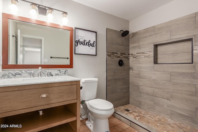 bathroom with a tile shower, vanity, and toilet