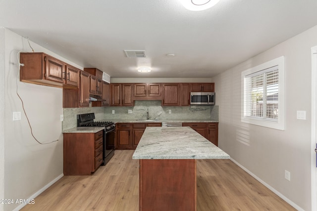 kitchen with light wood-type flooring, a center island, sink, decorative backsplash, and stainless steel appliances