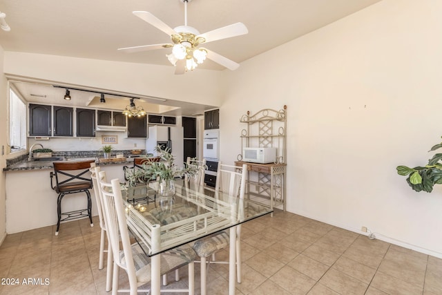 dining area featuring ceiling fan, light tile patterned floors, sink, and vaulted ceiling