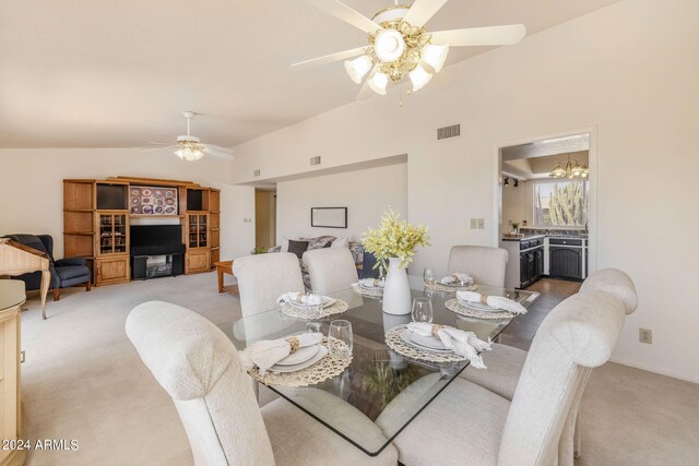 dining area with carpet flooring, visible vents, baseboards, ceiling fan with notable chandelier, and vaulted ceiling