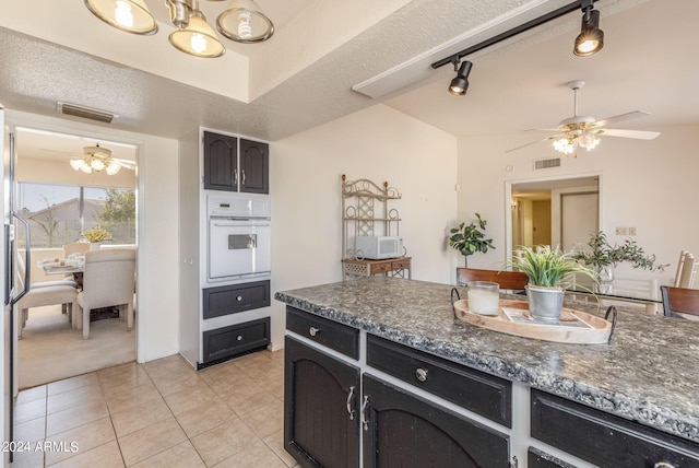 kitchen featuring ceiling fan with notable chandelier, white appliances, a textured ceiling, and light tile patterned floors