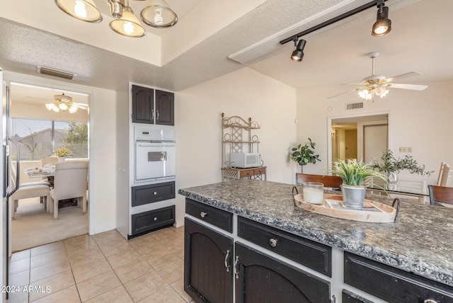 kitchen featuring visible vents, dark countertops, ceiling fan with notable chandelier, and white appliances