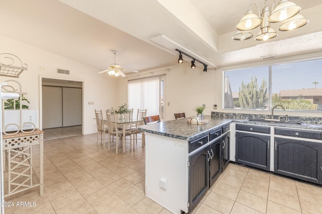 kitchen featuring ceiling fan with notable chandelier, kitchen peninsula, light tile patterned floors, and sink