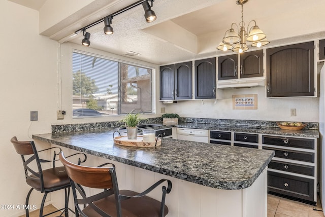 kitchen featuring dishwasher, a textured ceiling, a peninsula, under cabinet range hood, and dark countertops