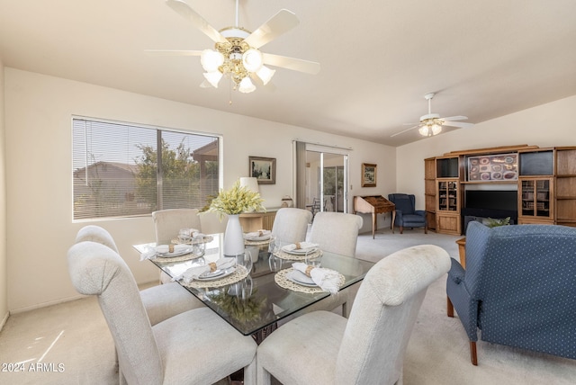 dining area with light carpet, lofted ceiling, ceiling fan, and a healthy amount of sunlight