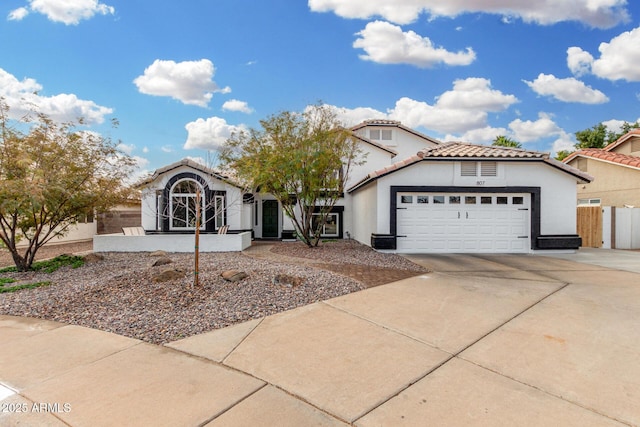 view of front facade with a garage, driveway, a tiled roof, and stucco siding