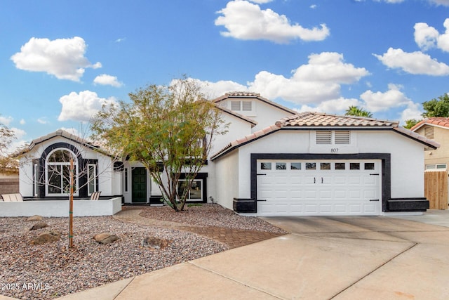 mediterranean / spanish house featuring a tile roof, stucco siding, concrete driveway, fence, and a garage