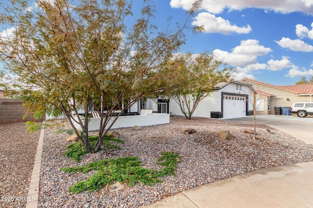 view of front of house with a garage, concrete driveway, a tiled roof, fence, and stucco siding