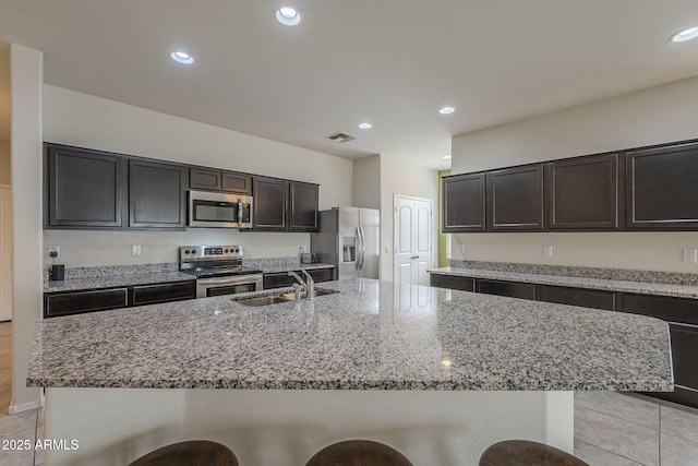 kitchen featuring an island with sink, stainless steel appliances, a breakfast bar, and sink