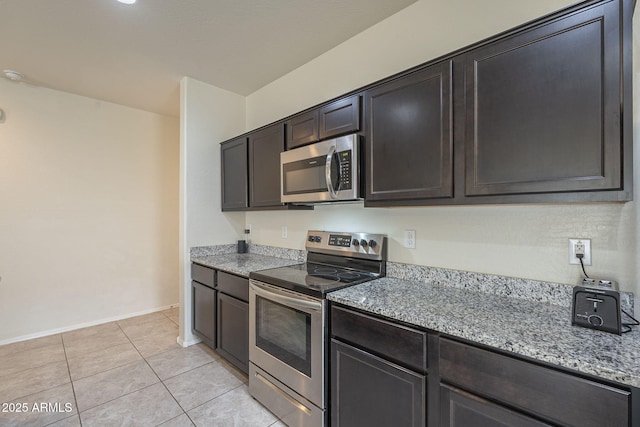 kitchen featuring light stone counters, appliances with stainless steel finishes, dark brown cabinets, and light tile patterned floors