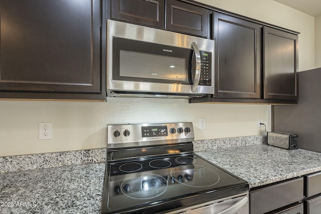 kitchen featuring light stone counters, dark brown cabinetry, and appliances with stainless steel finishes