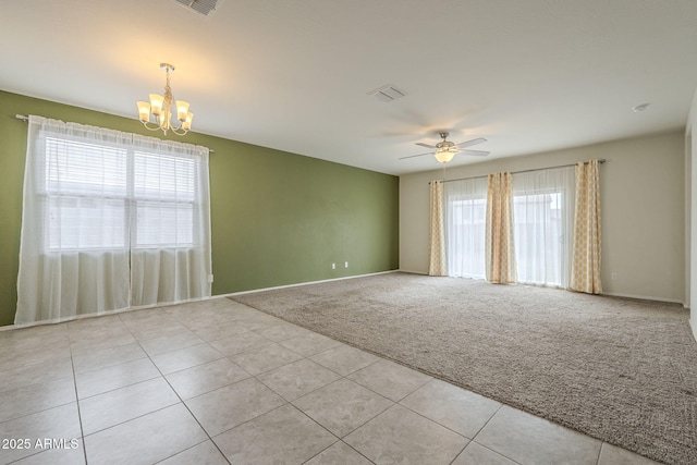 carpeted spare room with ceiling fan with notable chandelier