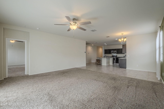 unfurnished living room with ceiling fan with notable chandelier, sink, and light carpet