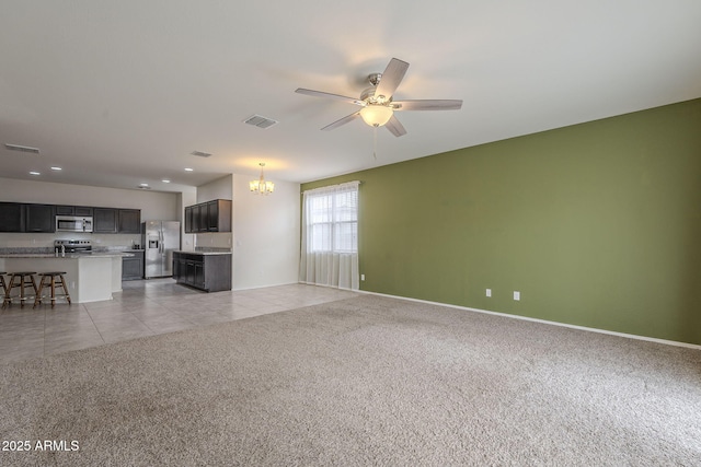 unfurnished living room with light colored carpet and ceiling fan with notable chandelier