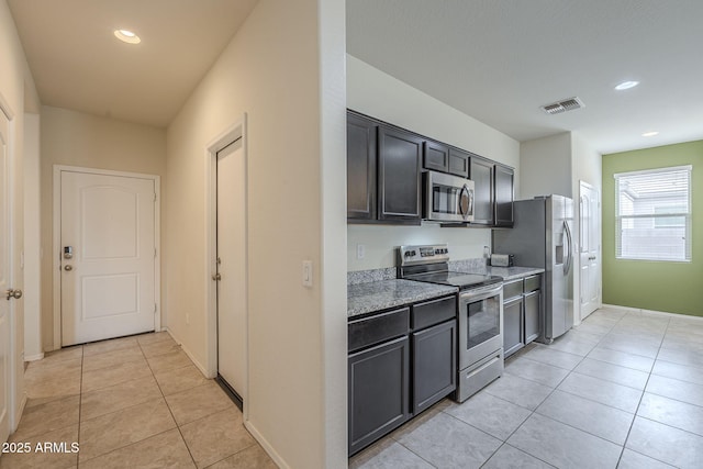 kitchen featuring appliances with stainless steel finishes, light tile patterned floors, and light stone counters