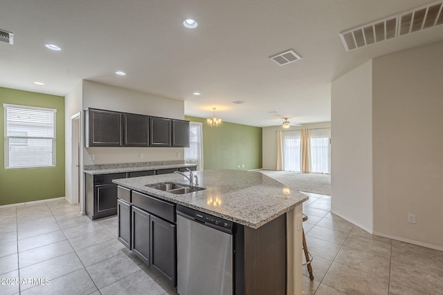 kitchen with dishwasher, sink, light tile patterned floors, and an island with sink