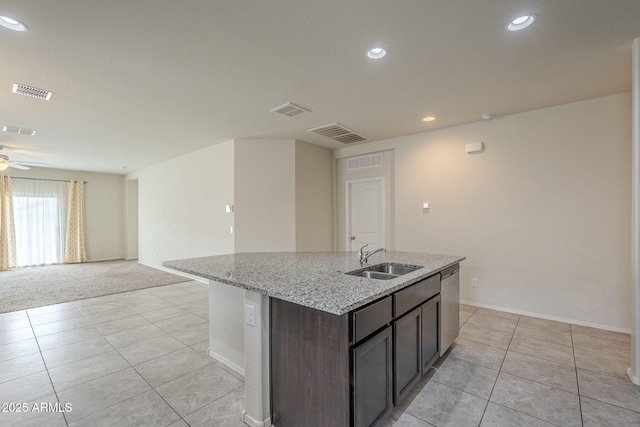 kitchen featuring sink, light stone counters, dark brown cabinets, a center island with sink, and dishwasher