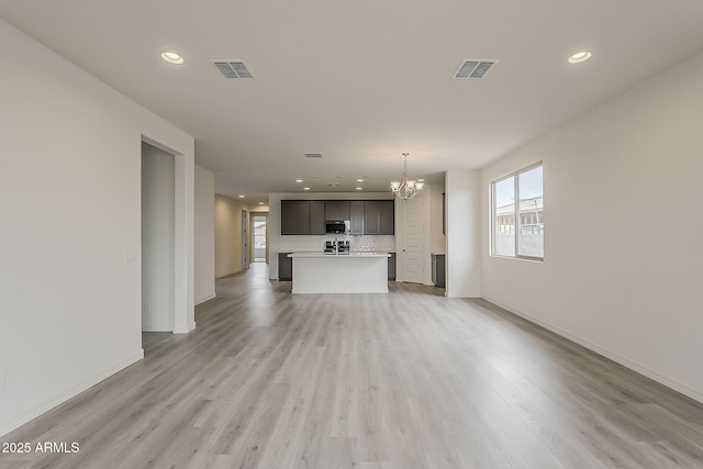 40030 W Bunker Dr, Maricopa, AZ 85138 - unfurnished living room with visible vents, light wood-type flooring, and an inviting chandelier