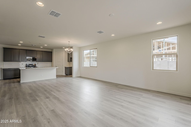 40030 W Bunker Dr, Maricopa, AZ 85138 - unfurnished living room featuring visible vents, light wood finished floors, a notable chandelier, and recessed lighting