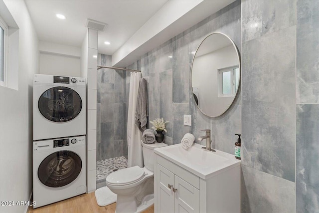 bathroom with a shower with curtain, wood-type flooring, tile walls, and stacked washer and clothes dryer