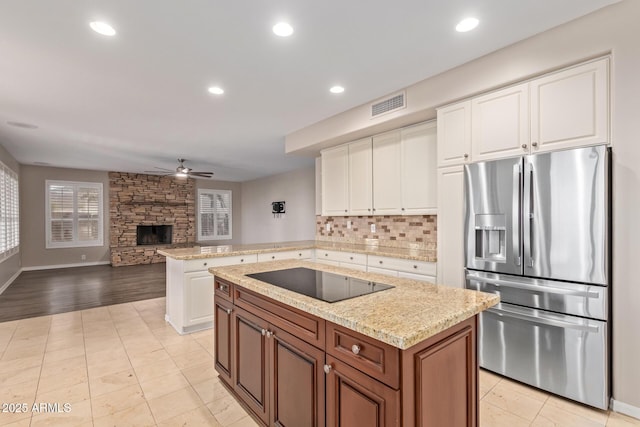 1211 E Desert Flower Ln, Phoenix, AZ 85048 - kitchen with stainless steel fridge with ice dispenser, black electric cooktop, a ceiling fan, a stone fireplace, and tasteful backsplash
