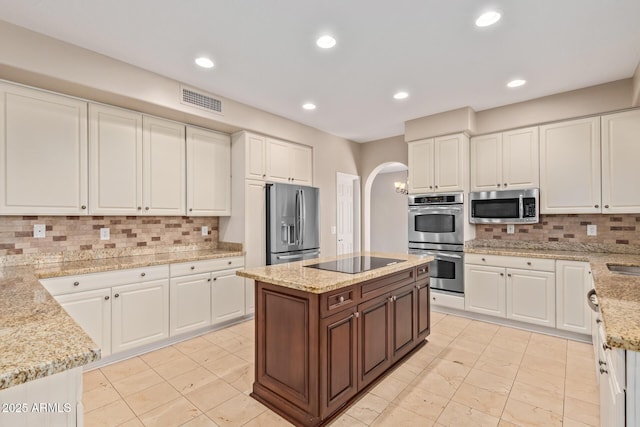 1211 E Desert Flower Ln, Phoenix, AZ 85048 - kitchen featuring appliances with stainless steel finishes, arched walkways, white cabinetry, decorative backsplash, and recessed lighting