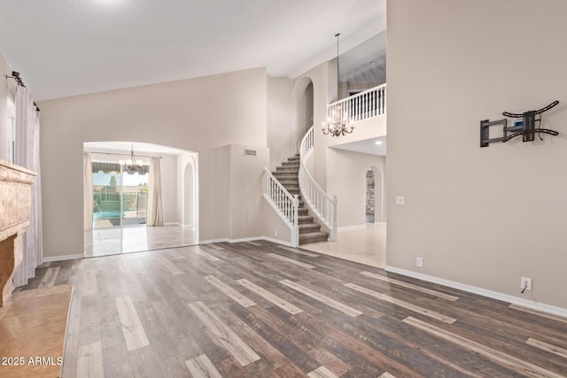 1211 E Desert Flower Ln, Phoenix, AZ 85048 - unfurnished living room featuring arched walkways, a chandelier, stairs, a high ceiling, and wood finished floors