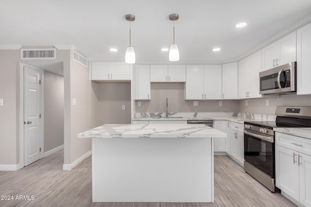 kitchen with crown molding, a center island, white cabinets, and appliances with stainless steel finishes