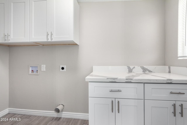 washroom featuring hookup for a washing machine, light hardwood / wood-style flooring, cabinets, and hookup for an electric dryer