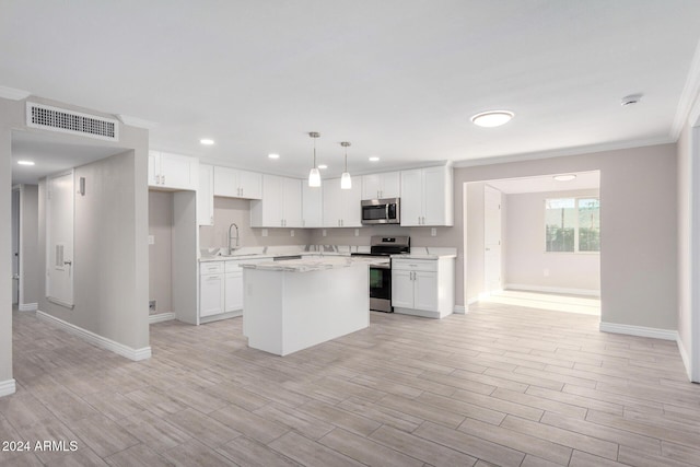 kitchen featuring ornamental molding, stainless steel appliances, white cabinets, a center island, and hanging light fixtures