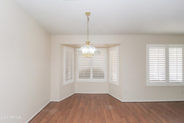 unfurnished room featuring hardwood / wood-style flooring and a chandelier