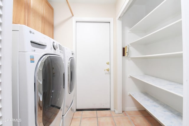 laundry room with cabinets, light tile patterned floors, and washer and clothes dryer