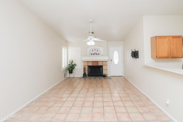 unfurnished living room featuring ceiling fan, light tile patterned flooring, and a tile fireplace